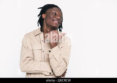 Young black man with dreadlocks smiling and pointing finger aside isolated over white background Stock Photo