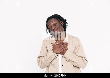 Black man with dreadlocks smiling while holding hands on his chest isolated over white background Stock Photo