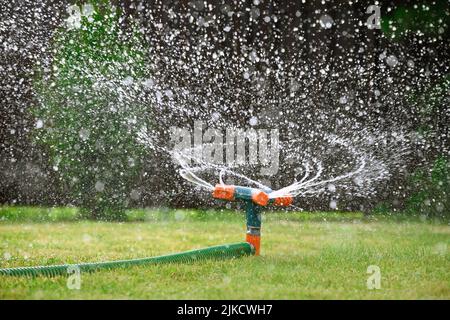 Green lawn automatic irrigation system in park. Watering lawn at heat summer. Stock Photo