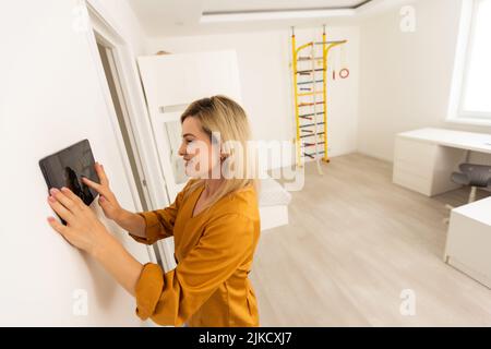 Woman using smart wall home control system. Stock Photo