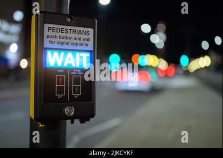 Pedestrian crossing button and illuminated wait sign with out of focus traffic in the background Stock Photo