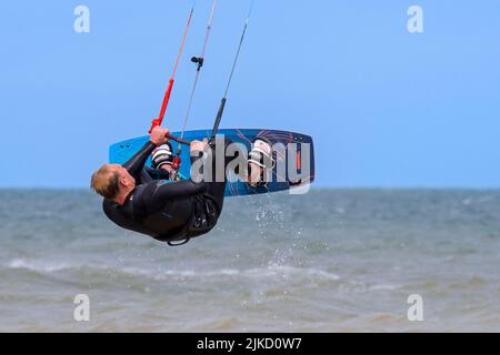Kitesurfing showing kiteboarder / kitesurfer on twintip board jumping on the North Sea on a windy day Stock Photo