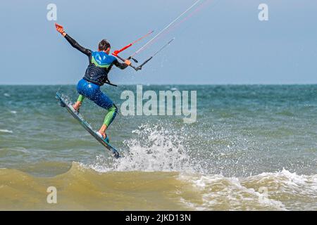 Kitesurfing showing kiteboarder / kitesurfer on twintip board jumping on the North Sea on a windy day Stock Photo