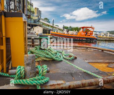 Mooring Bollard with rope on pier by the sea. Green Port rope. Mooring rope. Rope for fastening ships and cargo. Nobody Stock Photo