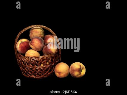 Image of a basket with a harvest of ripe peaches on a black background Stock Photo