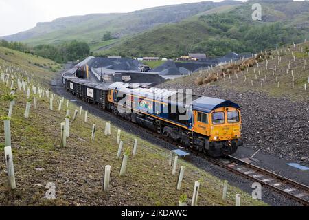 A Class 66 diesel locomotive with a train of stone waggons, being loaded at Arcow Quarry, Helwith Bridge, North Yorkshire. Stock Photo