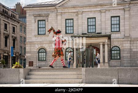Montreal, Canada - July 13, 2022: Actor dressed in Scottish military uniform in front of Place Royale playing bagpipes Stock Photo