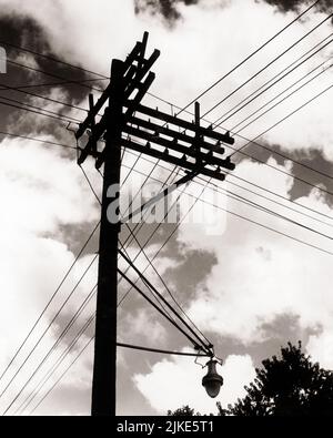 1930s SILHOUETTE GRAPHIC PATTERN ELECTRIC POWER LINES AND STREET LIGHT LAMP ON WOOD POLL VIEWED FROM BELOW AGAINST CLOUDS IN SKY - i3143 HAR001 HARS CONCEPTUAL COMPLEX SYMBOLIC CONCEPTS GROWTH POLL BLACK AND WHITE GRAPHIC EFFECT HAR001 OLD FASHIONED PUBLIC UTILITY REPRESENTATION Stock Photo