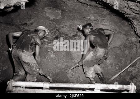 1940s TWO AFRICAN-AMERICAN MEN MINERS DIGGING HAND SHOVELING BAUXITE ROCK SOURCE OF ALUMINUM AND GALLIUM IN A MINE ARKANSAS USA - i3517 PUN001 HARS UNITED STATES OF AMERICA DANGER MALES RISK PROFESSION HAZARD MAIN B&W MINE NORTH AMERICA GOALS LOADING NORTH AMERICAN SKILL OCCUPATION SKILLS SHOVELING HIGH ANGLE DANGEROUS HARD HAT AFRICAN-AMERICANS AFRICAN-AMERICAN AND ARKANSAS CAREERS MINERS POWERFUL BLACK ETHNICITY LABOR WORLD WAR TWO RISKY WORLD WAR II IN OF EMPLOYMENT HAZARDOUS OCCUPATIONS PERIL UNSAFE CONCEPTUAL CONTENT WORLD WAR 2 ALUMINUM INFRASTRUCTURE SAFETY HELMET EMPLOYEE JEOPARDY Stock Photo