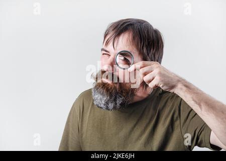 Curious bearded man see through magnifying glass. Science and curiosity concept. Stock Photo