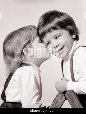 1960s TWO YOUNG GIRLS LITTLE SISTER EITHER WHISPERING IN OLDER ONE ON THE EAR OR KISSING HER ON CHEEK - j13192 HAR001 HARS SIBLINGS SISTERS B&W CHEERFUL SIBLING SMILES JOYFUL OR PERSONAL ATTACHMENT AFFECTION EMOTION JUVENILES PECK SMOOCH BABY GIRL BLACK AND WHITE CAUCASIAN ETHNICITY HAR001 OLD FASHIONED Stock Photo