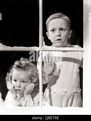 1940s TWO SAD KIDS BOY AND GIRL WEARING PAJAMAS LOOKING OUT A WINTER SNOWY WINDOW  - j1332 HAR001 HARS WORRY FAMILIES LIFESTYLE FEMALES BROTHERS STUDIO SHOT MOODY HOME LIFE COPY SPACE FRIENDSHIP HALF-LENGTH PERSONS MALES PAJAMAS SIBLINGS SISTERS TROUBLED SNOWY B&W CONCERNED SADNESS WINTERTIME DREAMS AND MOOD SIBLING CONCEPTUAL GLUM BABY SISTER WINTERY DISAPPOINTED GROWTH MISERABLE TOGETHERNESS YOUNGER BABY GIRL BIG BROTHER BLACK AND WHITE CAUCASIAN ETHNICITY HAR001 OLD FASHIONED Stock Photo
