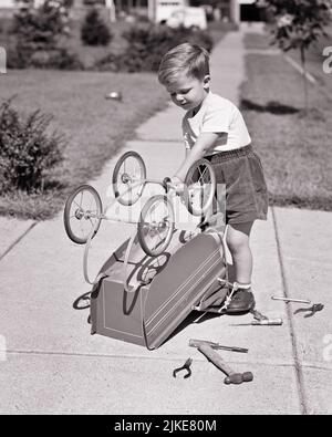 1940s LITTLE BOY REPAIRING TOY BABY CARRIAGE ON SUBURBAN SIDEWALK USING LOTS OF TOOLS LYING ON GROUND WEARING SHORTS AND T-SHIRT - j3643 HAR001 HARS JOBS HOME LIFE COPY SPACE FULL-LENGTH GROUND INSPIRATION MALES WHEELS MECHANICAL FIXING B&W GOALS CARRIAGE SKILL OCCUPATION SKILLS HIGH ANGLE DISCOVERY AND OCCUPATIONS USING REPAIRING LOTS CURIOUS FIX REPAIRMAN SUPPORT SINCERE T-SHIRT FOCUSED GROWTH INTENSE JUVENILES SOLUTIONS BABY CARRIAGE BLACK AND WHITE CAREFUL CAUCASIAN ETHNICITY EARNEST ENGINEERING HANDYMAN HAR001 INTENT OLD FASHIONED UPSIDE DOWN Stock Photo