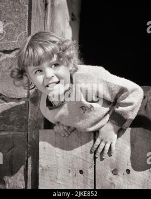 1940s 1950s CHARMING LITTLE GIRL DETERMINED TO CLIMB OVER A WOODEN FENCE - j497 HAR001 HARS EXPRESSIONS B&W TEMPTATION HEAD AND SHOULDERS ADVENTURE STRENGTH EFFORT TOMBOY ESCAPING CONCEPTUAL ATHLETES ESCAPE STRUGGLE DETERMINED JUVENILES BLACK AND WHITE CAUCASIAN ETHNICITY CHANCE HAR001 OLD FASHIONED Stock Photo