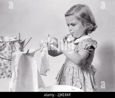Little girl hanging doll clothes on a washing line Stock Photo - Alamy