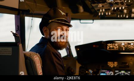 Portrait of airplane captain preparing to takeoff and fly using dashboard command in cockpit. Control panel with buttons and handle to start engine and travel, airline service. Stock Photo