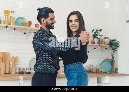 Couple slow dancing in the kitchen smiling boyfriend smiling watching girlfiend looking at camera with wide smile. Indoor shot. High quality photo Stock Photo