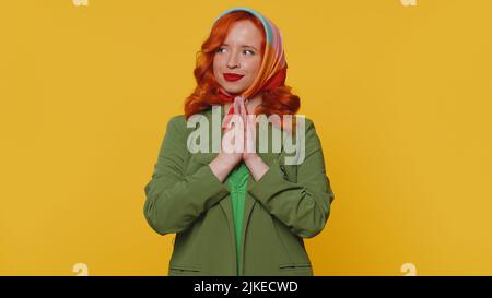 Sneaky cunning woman with tricky face gesticulating and scheming evil plan, thinking over devious villain idea, cunning cheats, jokes and pranks. Redhead girl on yellow studio background alone indoors Stock Photo