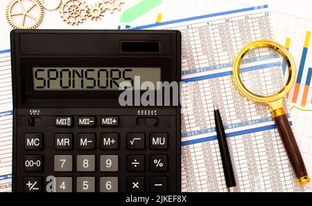 On a light table are notebooks, a magnifying glass, an alarm clock, glasses, and a pen. And in the center is a notebook with the text SPONSOR Stock Photo