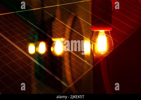 detail of several light bulbs lit in yellow color and warm tone, dark background - plates with cells for capturing solar energy Stock Photo
