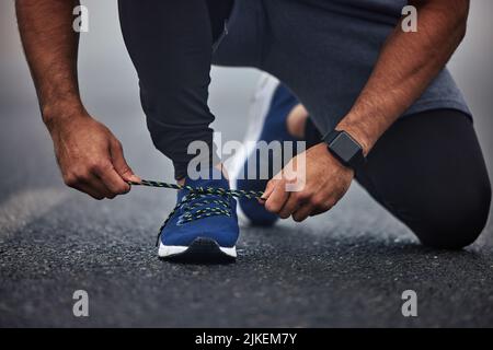 Are you ready for this. Closeup shot of an unrecognisable man tying his shoelaces while exercising outdoors. Stock Photo