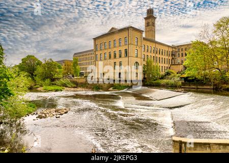 5 May 2022: Saltaire, Bradford, UK - Salt's Mill and the weir on the River Aire in spring. Stock Photo