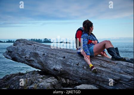 Mature couple sitting on a tree trunk on the beach Stock Photo