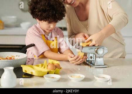 Mother and son using pasta machine to prepare spaghetti for dinner Stock Photo