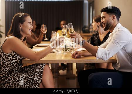 Happy New Year, babe. a happy young couple sitting together and toasting with champagne during a New Years dinner party. Stock Photo