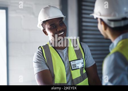 Leave it to me. two young contractors standing in the warehouse together and having a discussion. Stock Photo