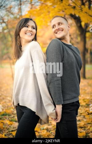 Young smiling couple having fun together on weekends in autumn park. Stock Photo