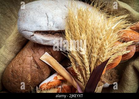 Freshly baked rye bread on linen fabric with wheat bouquet. Stock Photo