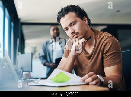 Thinking up some new ideas. a young businessman looking thoughtful in an office. Stock Photo