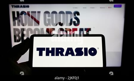 Person holding smartphone with logo of US retail company Thrasio LLC on screen in front of website. Focus on phone display. Stock Photo