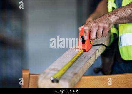 The rest dont measure up to him. a builder using a measuring tape at a construction site. Stock Photo