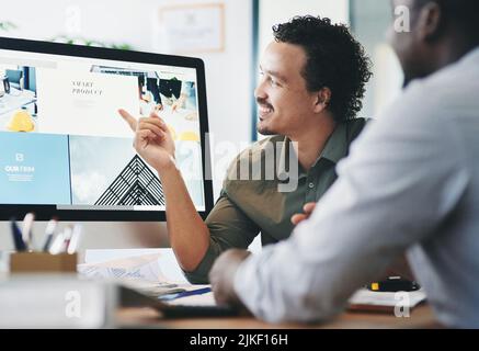 This is the topic I was talking about earlier. two young businessmen having a discussion in an office. Stock Photo