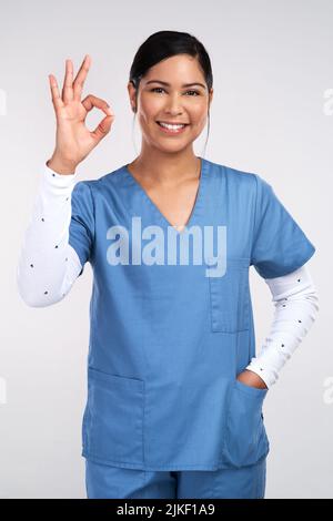 Deeper than the deepest of connections, ill travel inside you. Portrait of a young doctor showing the ok sign against a white background. Stock Photo