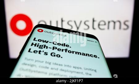 Smartphone with website of low-code software company OutSystems on screen in front of business logo. Focus on top-left of phone display. Stock Photo