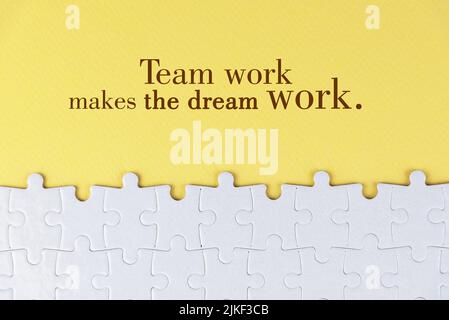 Business motivational quote - Team work makes the dream work. On yellow background of white jig saw puzzle missing pieces. Success team work concept. Stock Photo