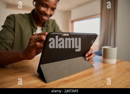 Young adult black African-American male drawing with pen on electronic tablet while working remotely from modern apartment. Graphic designer, digital Stock Photo