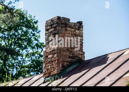 Old brick chimney in need of repair on a roof. Heating and fire safety concept. Stock Photo