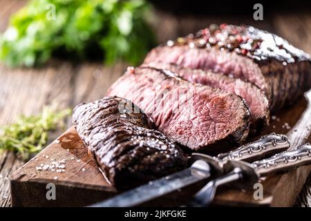 Juicy medium-grilled beef steak on a cutting board with a knife and fork. Stock Photo