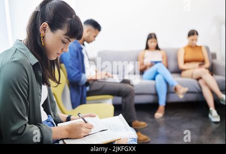 Trying to get my head in the game. ta group of people using their devices while waiting to be interviewed in a modern office. Stock Photo