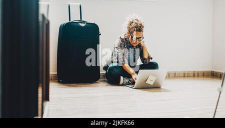 One woman sitting on the floor in an empty home apartment flat using laptop computer. Concept of new house and moving after mortgage loan. Real estate Stock Photo