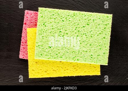 Three cellulose sponges on a slate stone, close-up, top view. Stock Photo