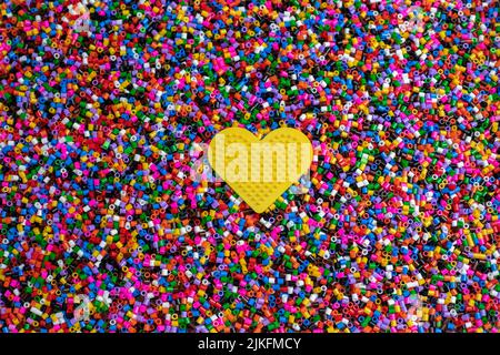 Set of multi-colored cylindrical plastic pieces to string on a yellow heart and form geometric shapes Stock Photo