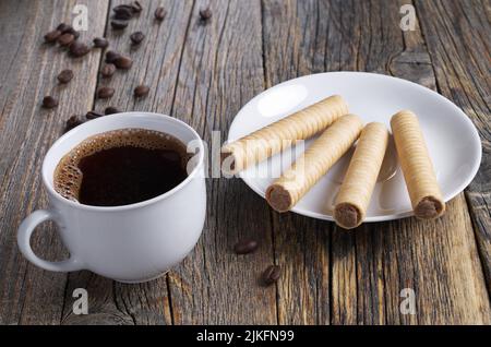 Cup of coffee and chocolate wafer stick rolls on old wooden background Stock Photo
