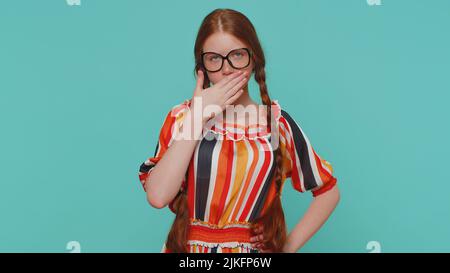 Offended redhead girl ginger in dress having misunderstanding, frustrated after quarrel, ignores and does not want to communicate, talk. Young ginger teenager child isolated on blue studio background Stock Photo