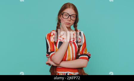 Redhead young girl touching sore cheek suffering from toothache cavities or gingivitis waiting for dentist appointment gums disease. Ginger teenager child studio shot isolated alone on blue background Stock Photo