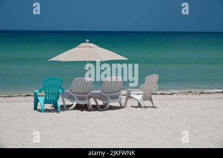 Parasol and sunbeds on empty beach in Progreso by blue ocean in the Caribbean. Vacation in Yucatan, Mexico. Stock Photo